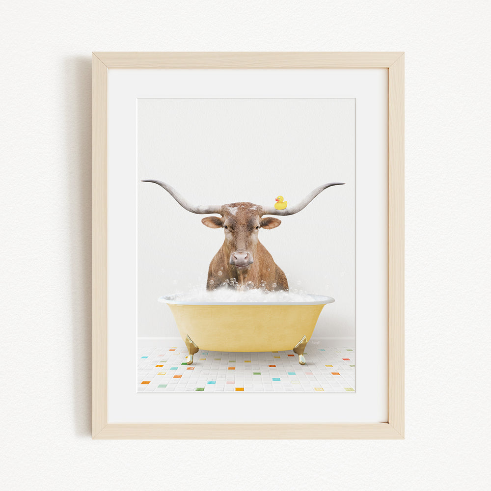 A brown cow with large horns is sitting in a yellow bathtub filled with bubbles, with a yellow duck perched on its head.