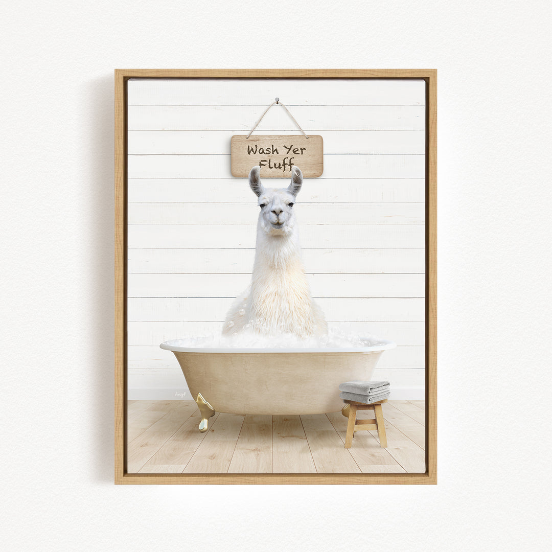 A white llama sitting in a bathtub filled with bubbles, with a sign above it that says "Wash Yer Fluff".