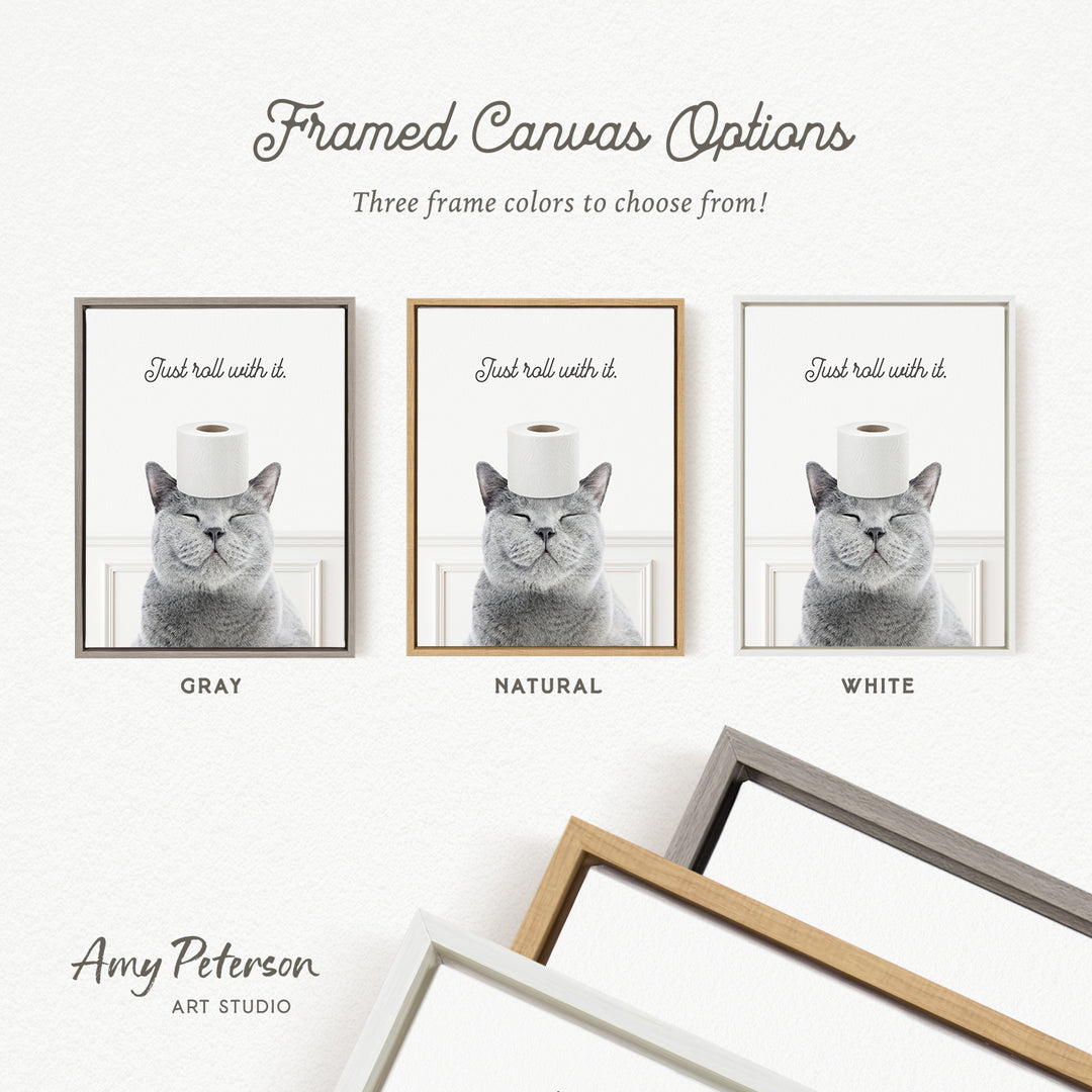 The image is a framed canvas with three different color options for the frame, including gray, natural, and white. The canvas features a cat with a roll of toilet paper on its head, and the text "Just roll with it" is displayed above the cat.