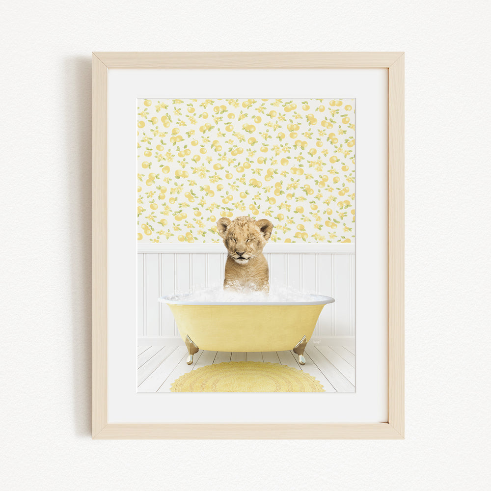 A young lion cub sitting in a yellow bathtub filled with water, surrounded by a yellow floral wallpaper.