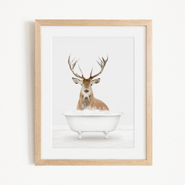 A deer with large antlers is sitting in a white bathtub filled with water, creating a whimsical and unexpected scene.