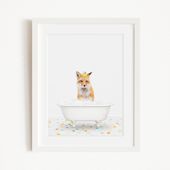 A red fox is sitting in a white bathtub filled with bubbles, with a yellow rubber duck perched on its head.