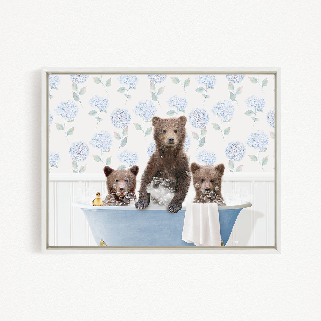 Three adorable brown bears sitting in a blue bathtub, surrounded by a floral patterned wall.