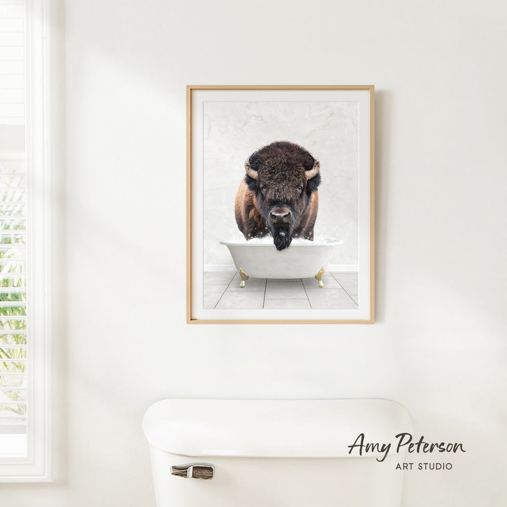 A framed image of a buffalo standing in a bathtub, with the text " Amy Peterson ART STUDIO" below the frame.