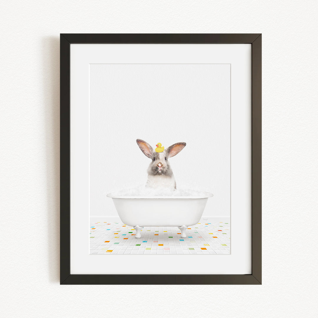 A white rabbit sitting in a white bathtub filled with bubbles, with a yellow rubber duck perched on its head.