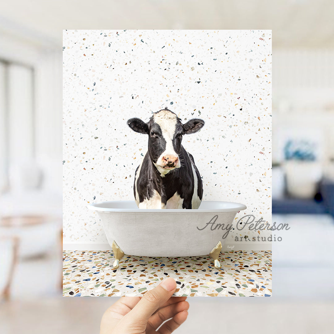 a hand holding up a card with a picture of a cow in a bathtub