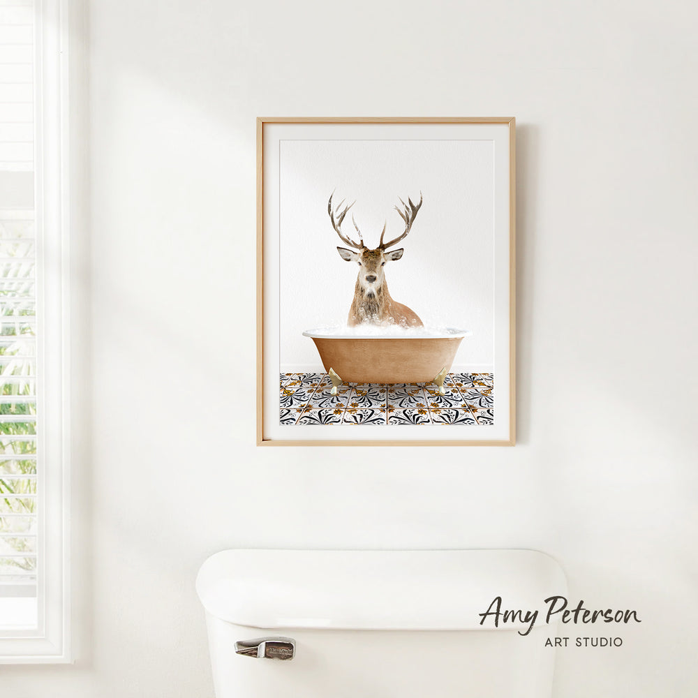 A framed image of a deer sitting in a bathtub, with a patterned tile floor beneath it.