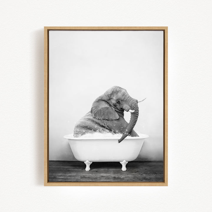 A black and white photograph of an elephant sitting in a bathtub filled with water.