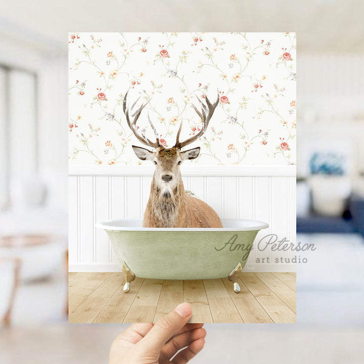 a hand holding up a photo of a deer in a bathtub