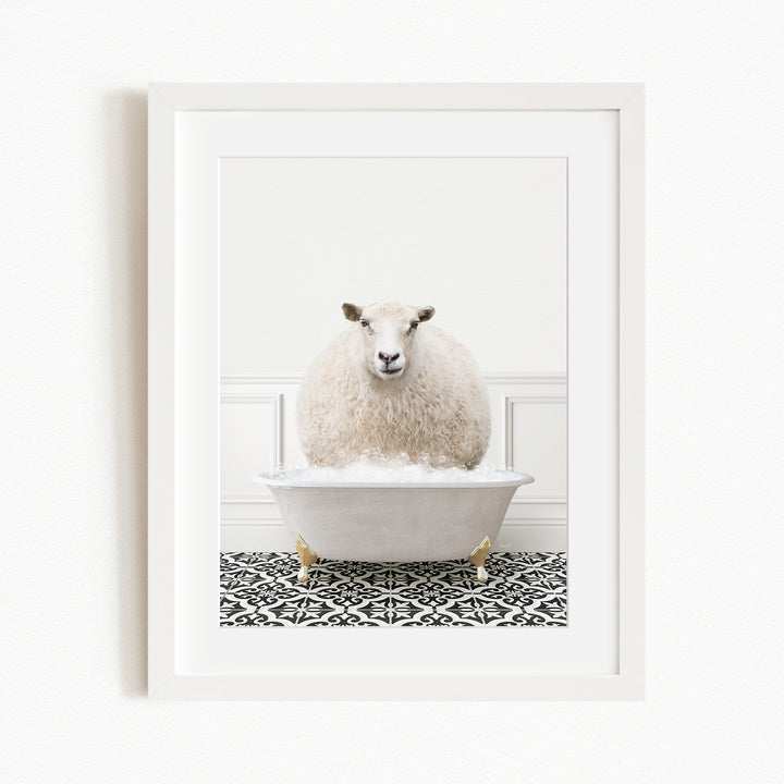 A fluffy white sheep sits in a white bathtub filled with bubbles, surrounded by a black and white patterned floor.