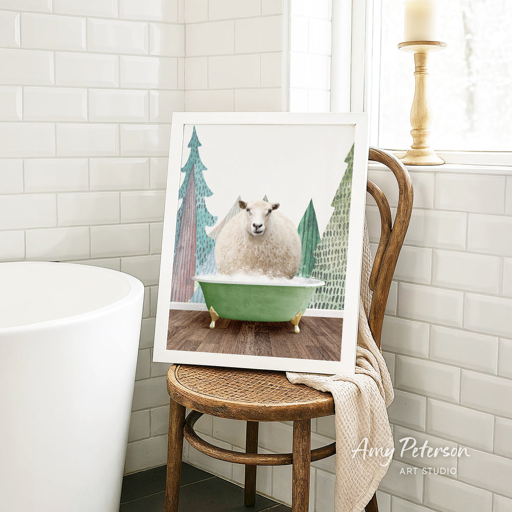A framed image of a sheep sitting in a green bathtub, surrounded by Christmas trees, is displayed on a wooden chair in a bathroom setting.