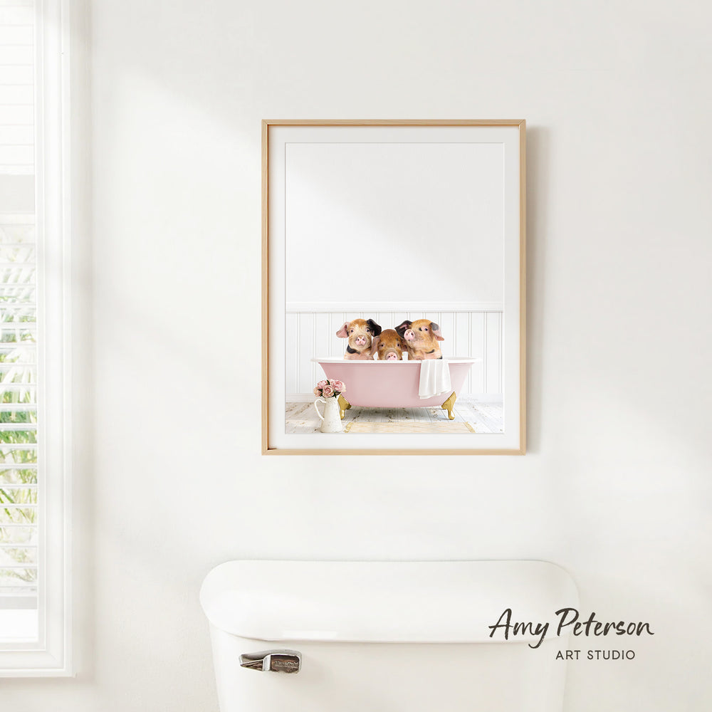 A framed image of two dogs sitting in a pink bathtub, with a window and a toilet visible in the background.