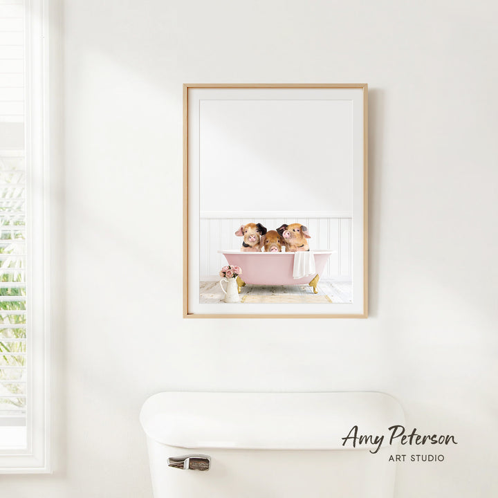 A framed image of two dogs sitting in a pink bathtub, with a window and a toilet visible in the background.