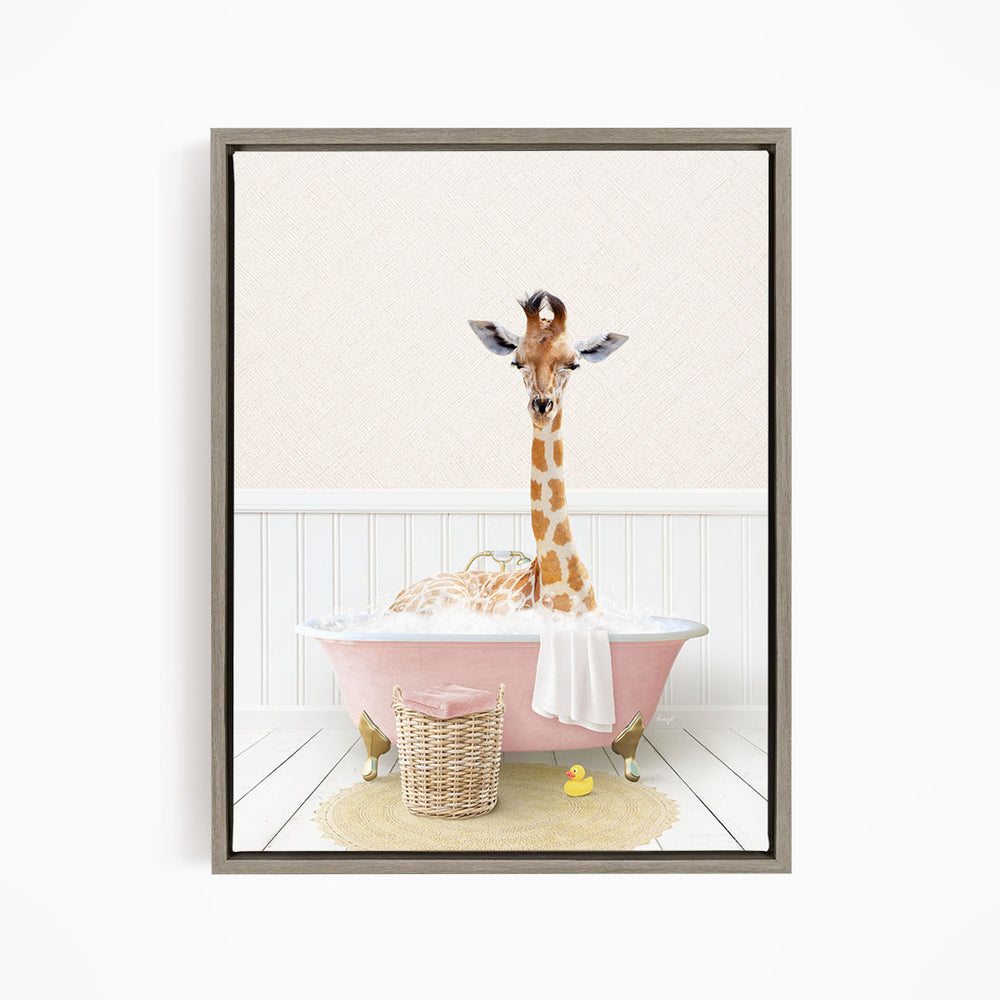 A giraffe is sitting in a pink bathtub filled with bubbles, surrounded by a yellow rubber duck and a wicker basket.