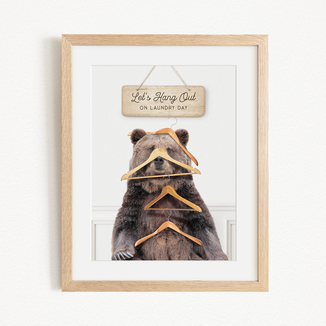 A framed image of a bear sitting in front of a sign that says "Let's Hang Out on Laundry Day".