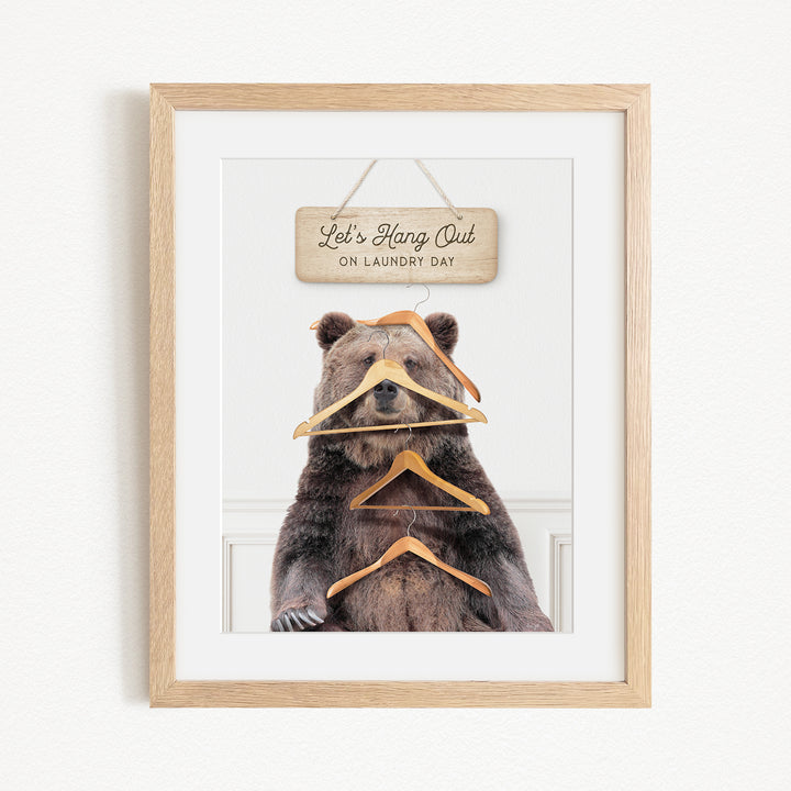 A framed image of a bear sitting in front of a sign that says "Let's Hang Out on Laundry Day".
