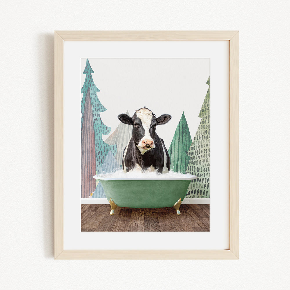 A black and white cow is sitting in a green bathtub, surrounded by trees and a forest-like background.