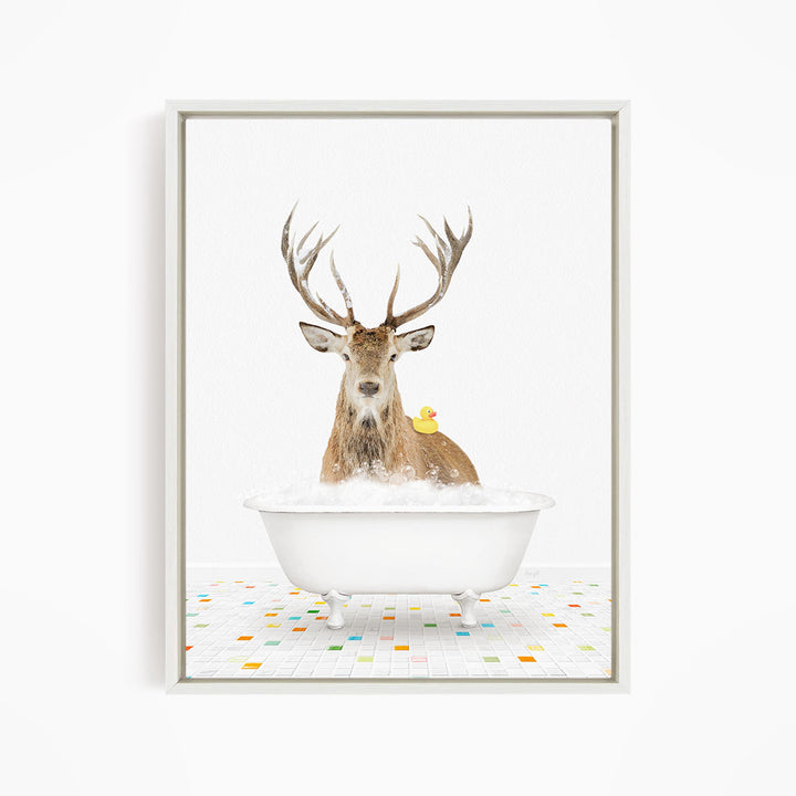 A deer with large antlers is sitting in a white bathtub filled with bubbles, with a yellow duck perched on its back.