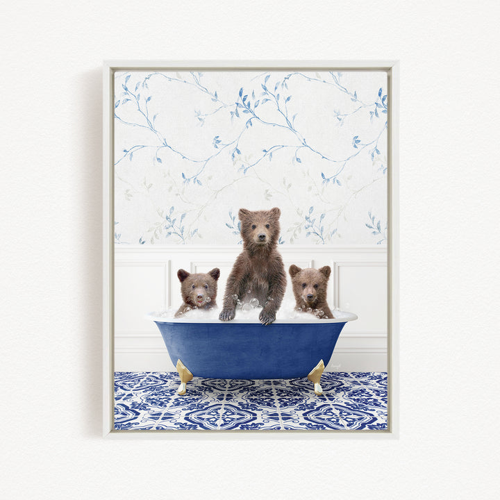 A framed image depicting three brown bears sitting in a blue bathtub, with a floral patterned wall behind them.