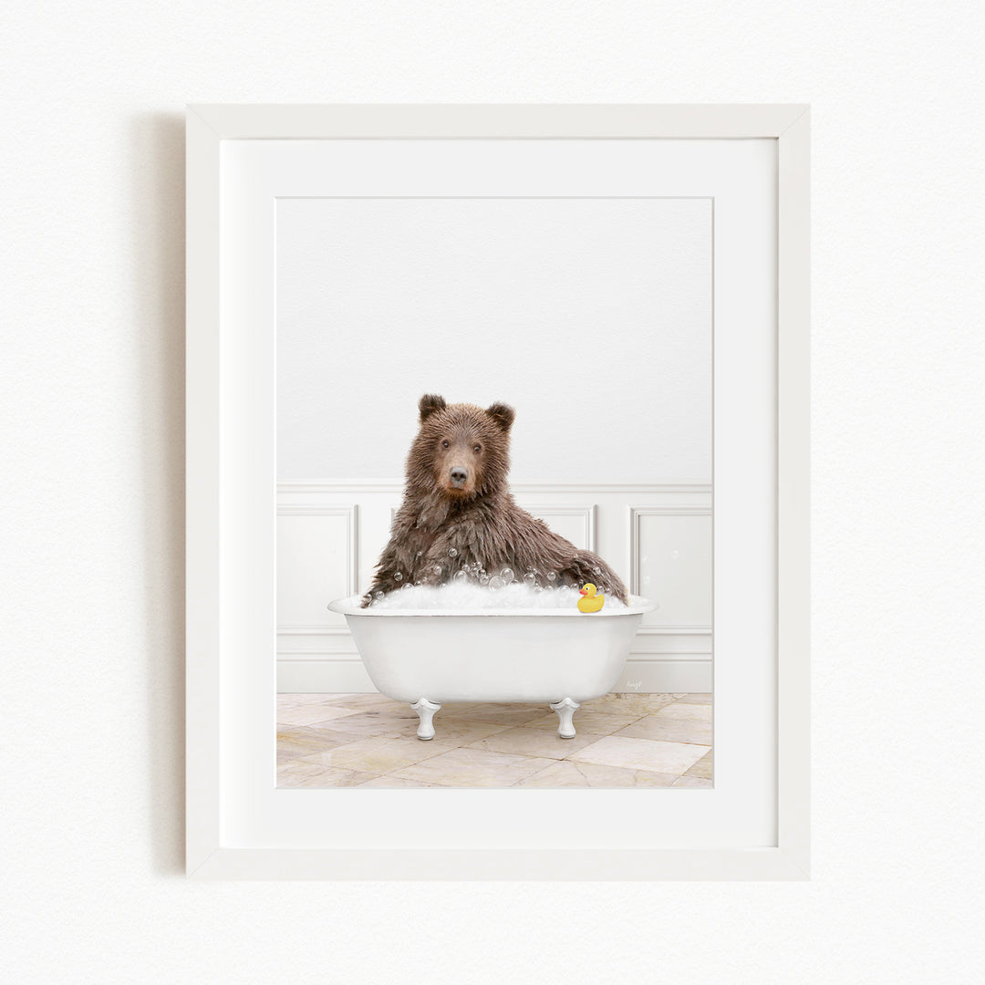 A brown bear sitting in a white bathtub filled with water and bubbles, with a yellow rubber duck floating in the water.