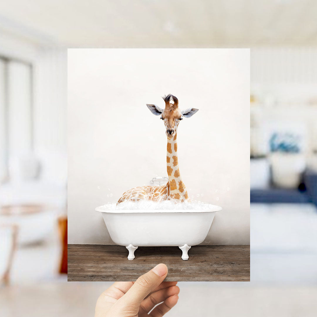 A giraffe sitting in a white bathtub filled with bubbles, with a blurred background suggesting a living room setting.