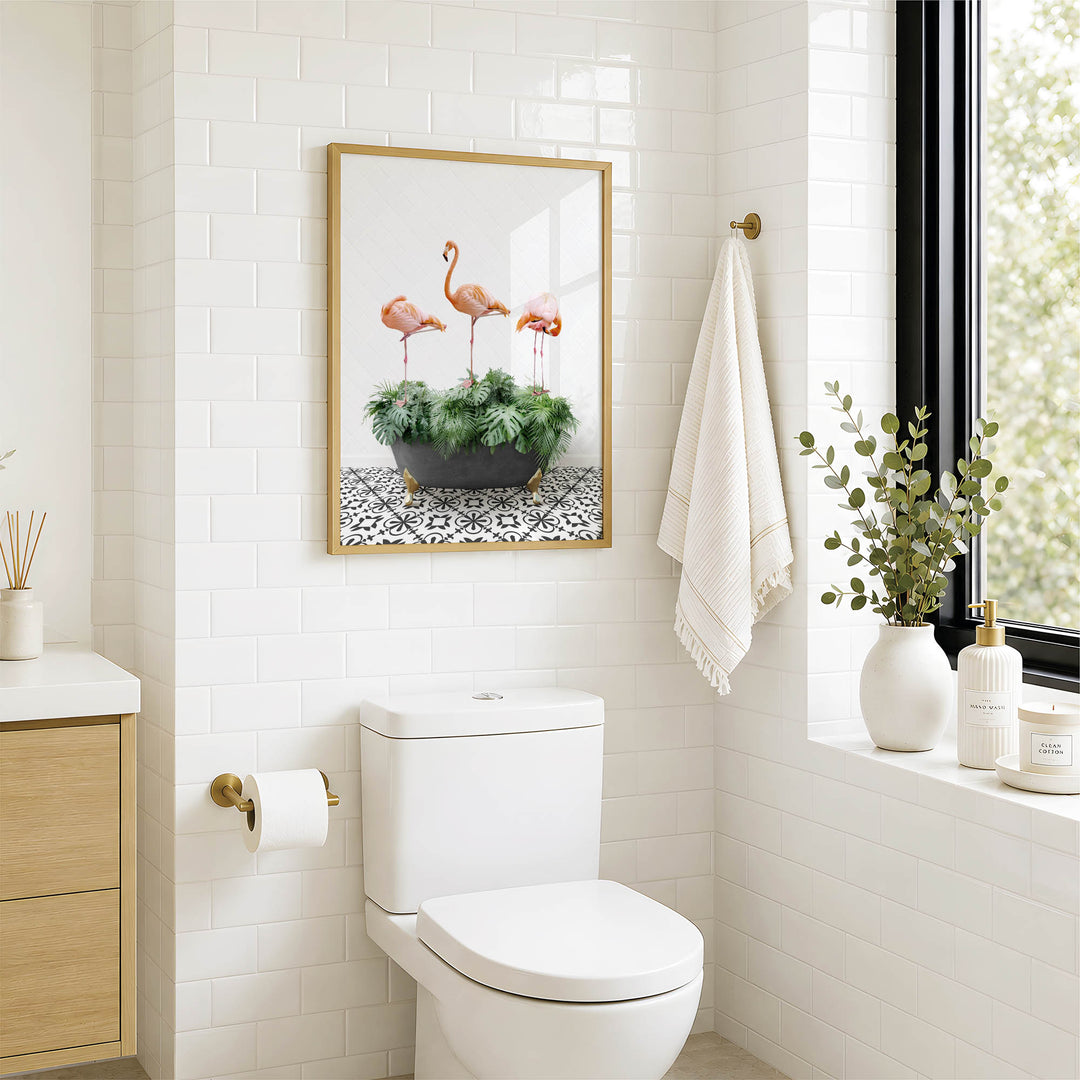 a bathroom with a white toilet, a framed picture of three pink flamingos on a green plant, and a window with a plant on the sill.