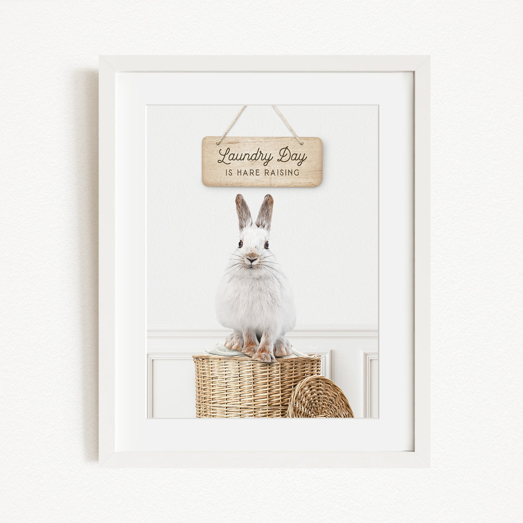 A white rabbit sitting on a wicker basket, with a wooden sign above that says "Laundry Day is here raising".