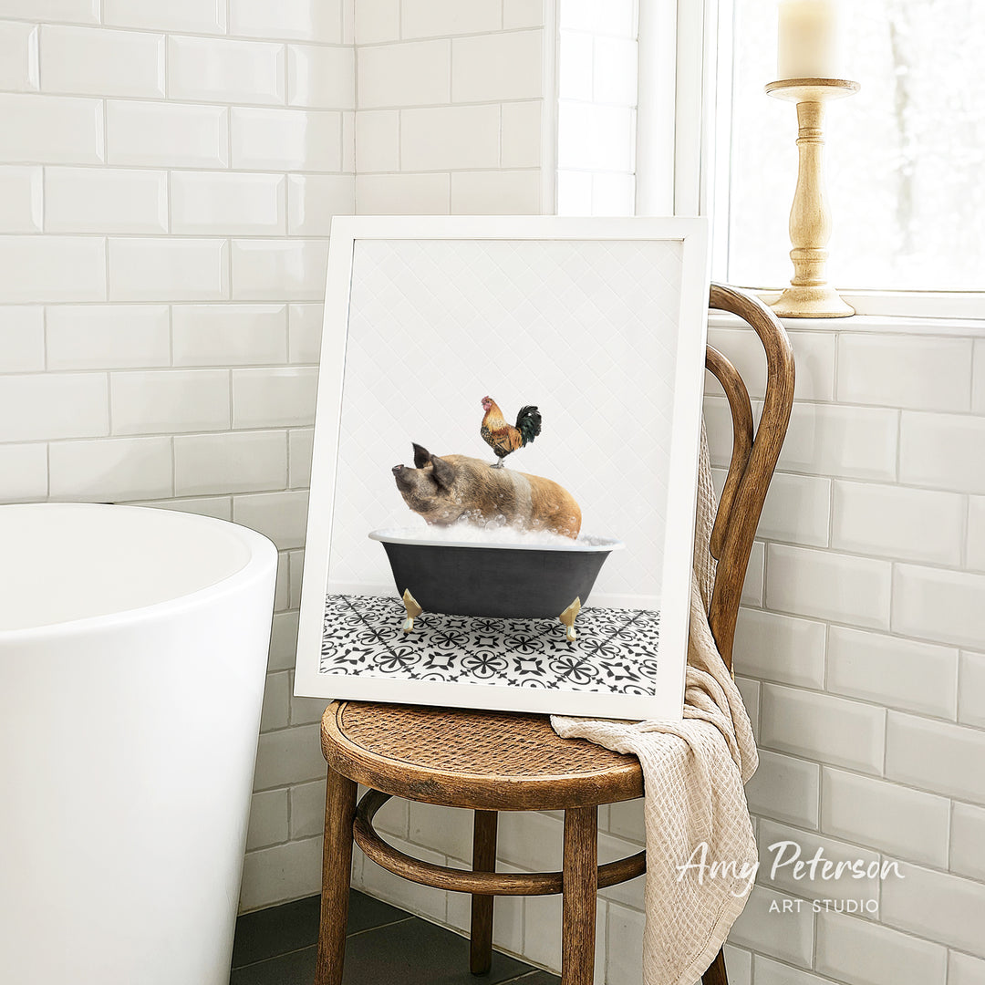 A framed image of a pig sitting in a bathtub, with a rooster perched on its back, is displayed on a wooden chair in a bathroom setting.