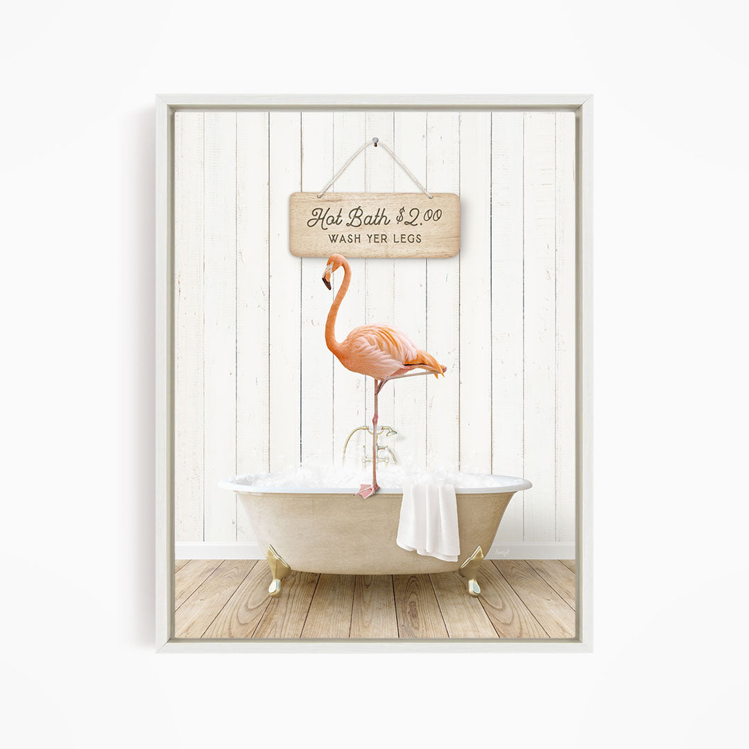 A framed image of a pink flamingo standing on a white bathtub, with a wooden sign above it that reads "Hot Bath $2.00 WASH YOUR LEGS".