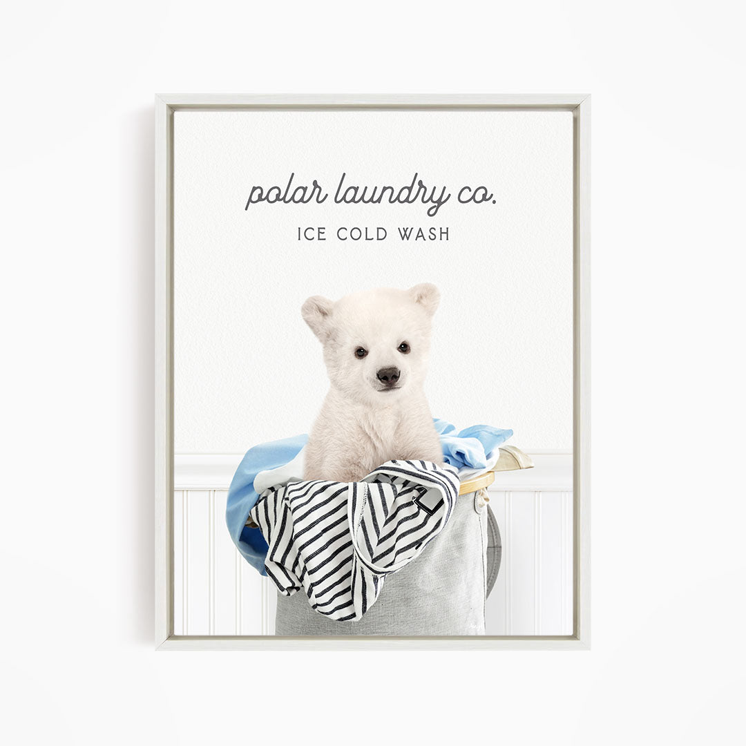 A white polar bear sitting in a laundry basket filled with clothes, with the text "polar laundry co. ICE COLD WASH" displayed above the image.