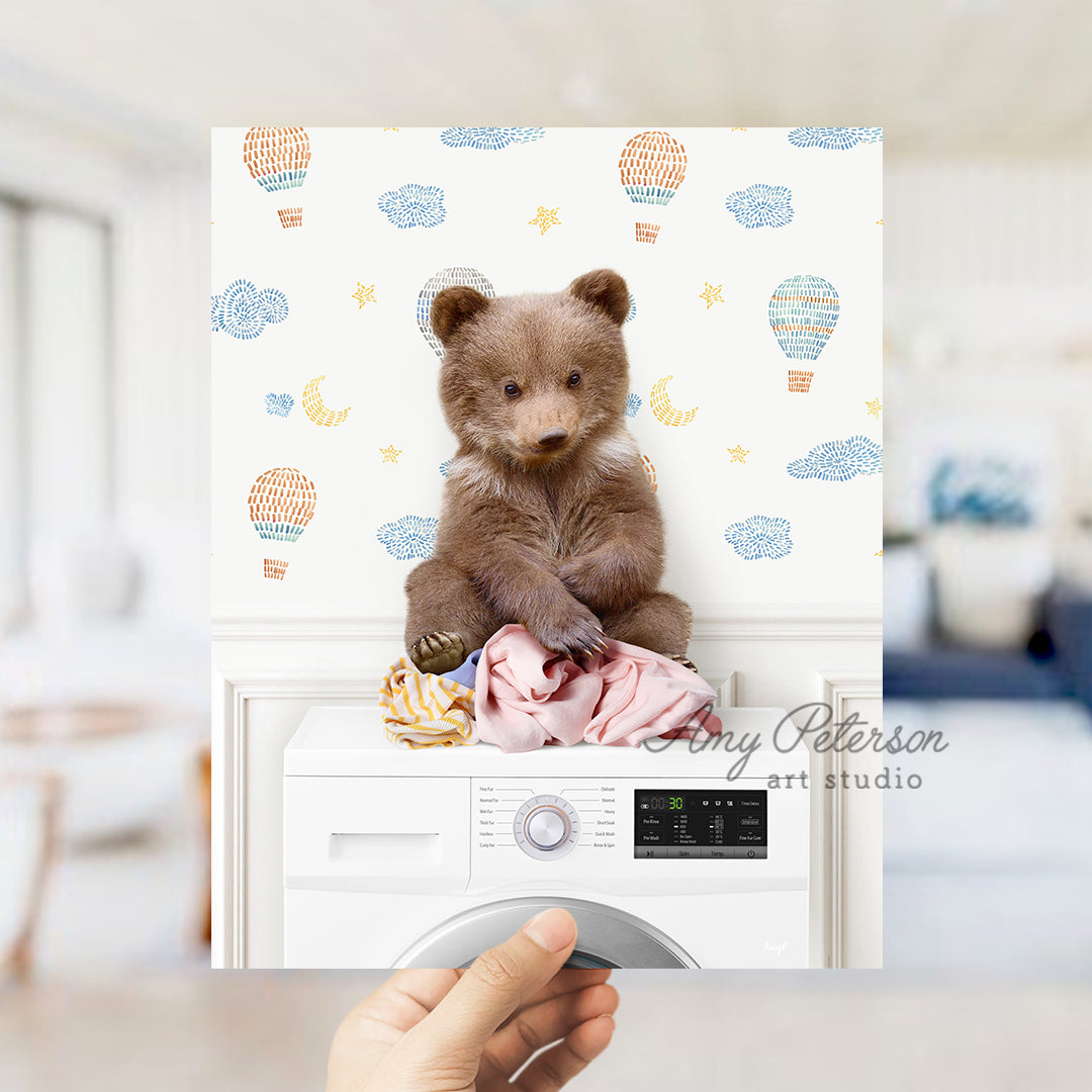 a teddy bear sitting on top of a washing machine