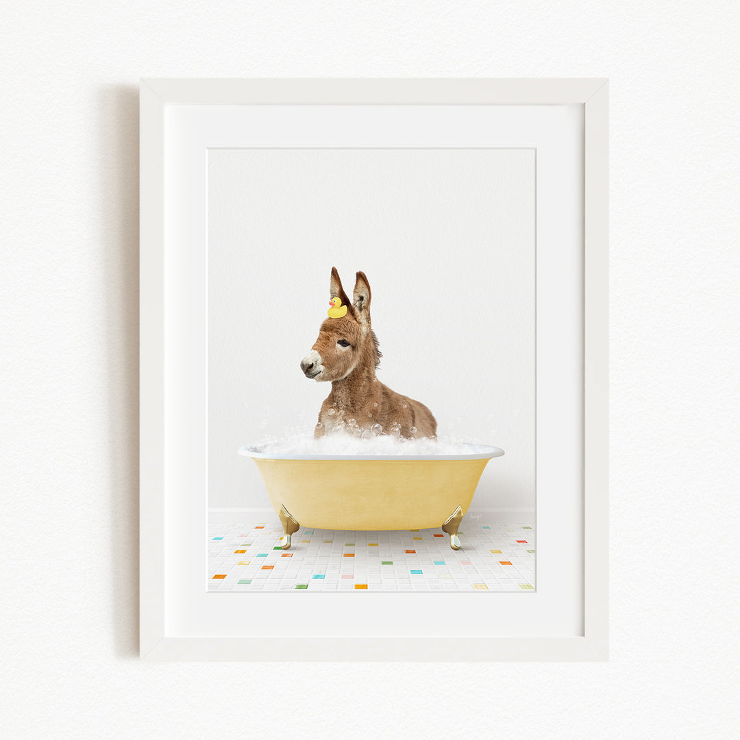 A donkey is sitting in a yellow bathtub filled with bubbles, with a yellow rubber duck floating on the water.