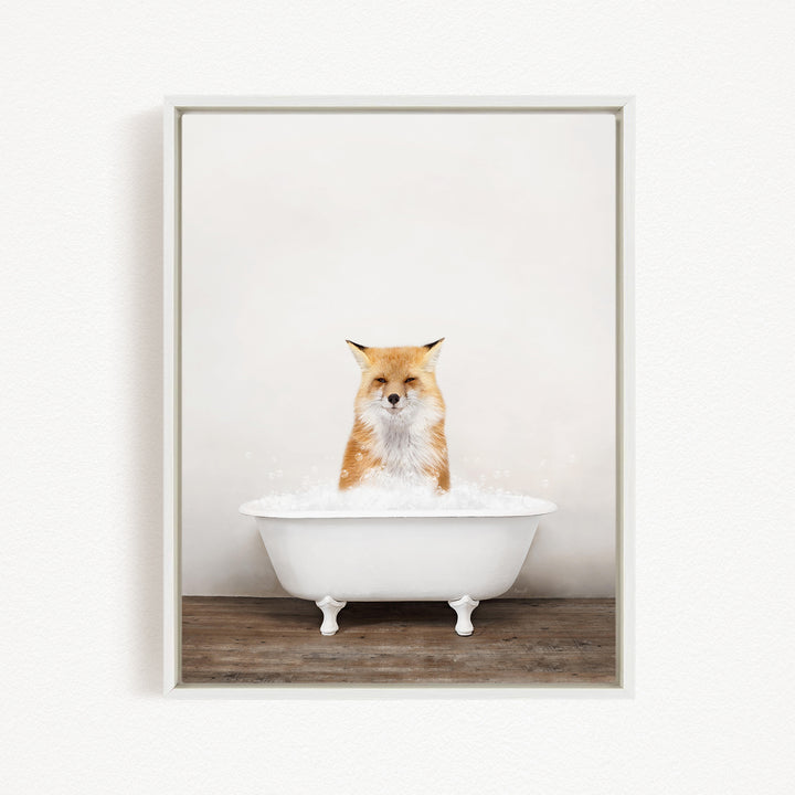 A red fox sitting in a white bathtub filled with bubbles, looking directly at the camera.