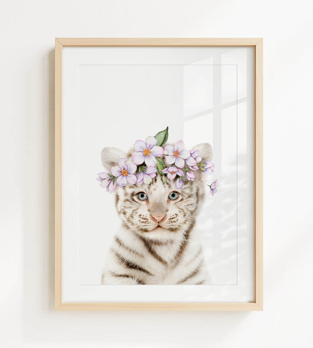A cute tiger cub wearing a flower crown on its head, with its eyes looking directly at the camera.