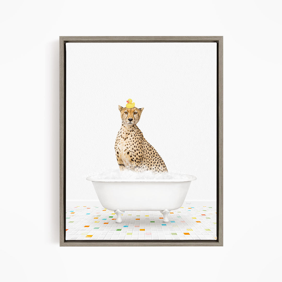 A cheetah sitting in a white bathtub filled with bubbles, wearing a yellow rubber duck hat.