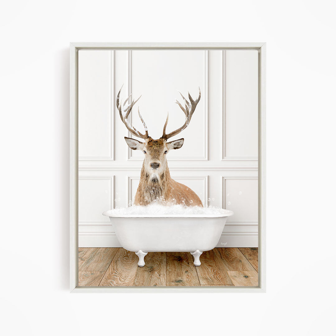 A deer with large antlers is sitting in a white bathtub filled with water, creating a whimsical and unexpected scene.