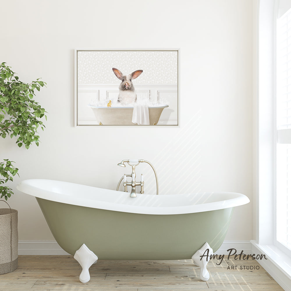 A green clawfoot bathtub with a white towel hanging over the side, set against a white wall with a framed image of a rabbit in a bathtub above it.
