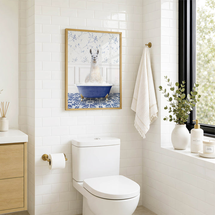 A bathroom with a white toilet, a framed picture of a llama in a bathtub, and a window with greenery outside.