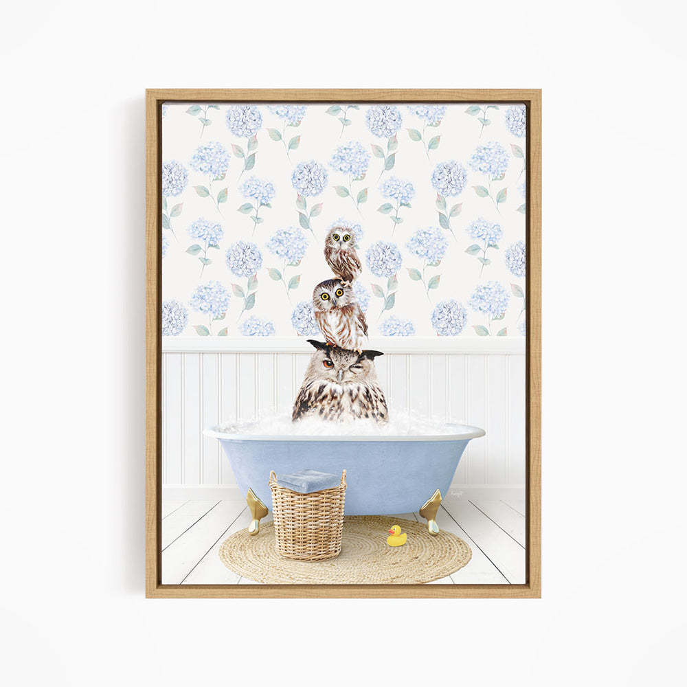 A framed image depicting three owls sitting in a bathtub filled with water, surrounded by a blue floral pattern on the wall.