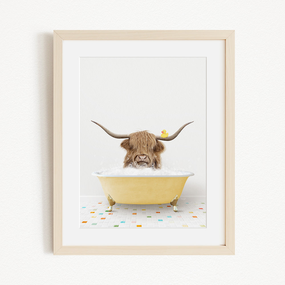 A brown cow with long horns is sitting in a yellow bathtub, with a rubber duck floating on the water.