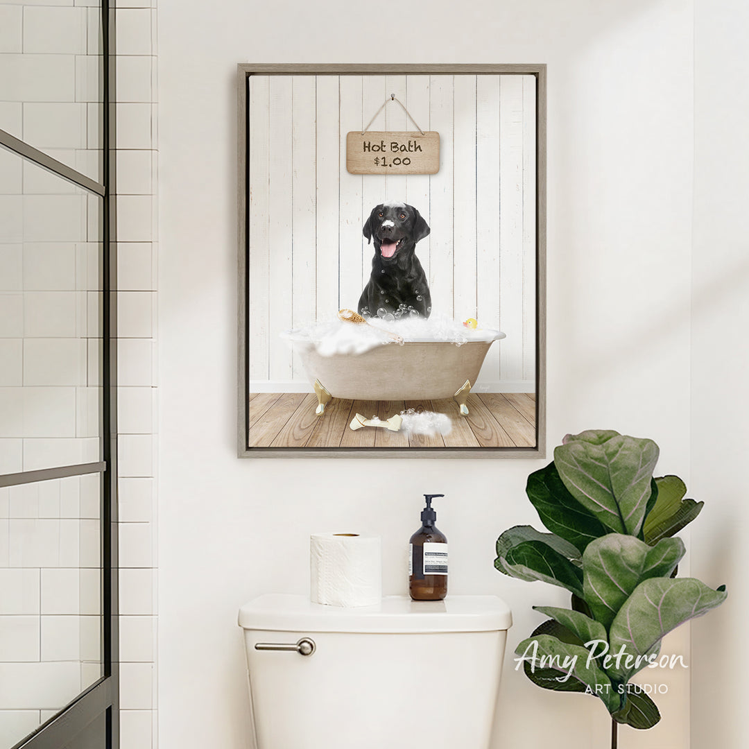 A framed image of a black dog sitting in a bathtub, with a sign above it that says "Hot Bath is Fun". The image is displayed in a bathroom setting, with a toilet and a potted plant visible.