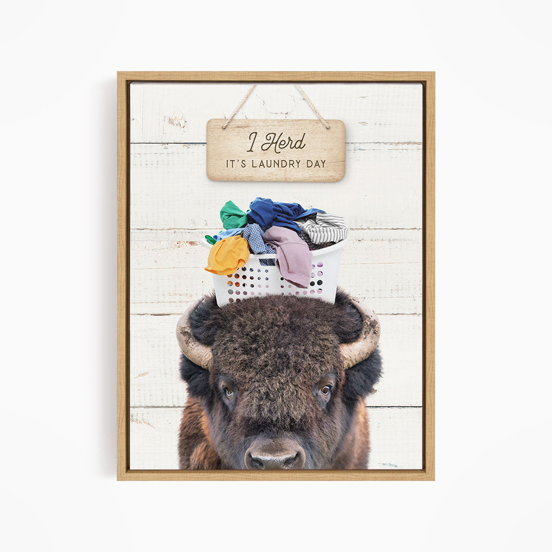 A buffalo with a basket of laundry on its head, accompanied by a wooden sign that says "It's laundry day".