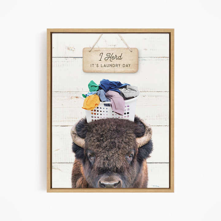A buffalo with a basket of laundry on its head, accompanied by a wooden sign that says "It's laundry day".