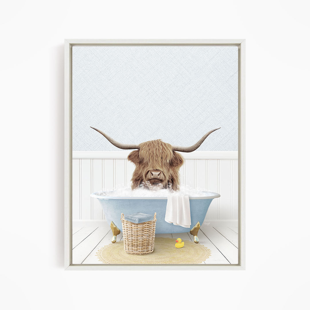 A brown cow with long horns is sitting in a blue bathtub filled with water, surrounded by a yellow rubber duck and a wicker basket.