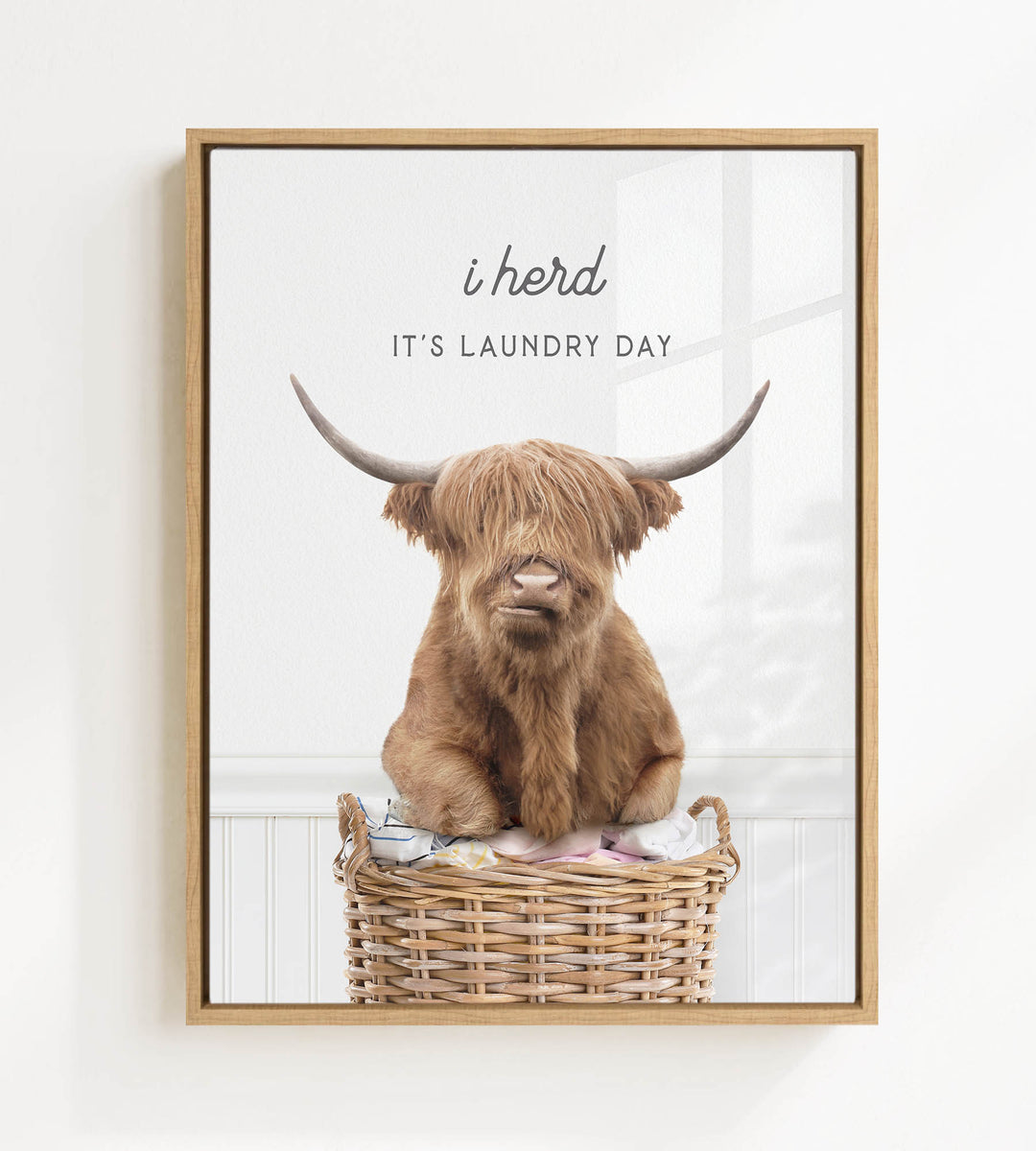 A brown cow with long horns is sitting in a wicker basket, with the text "i herd, it's laundry day" displayed above the image.