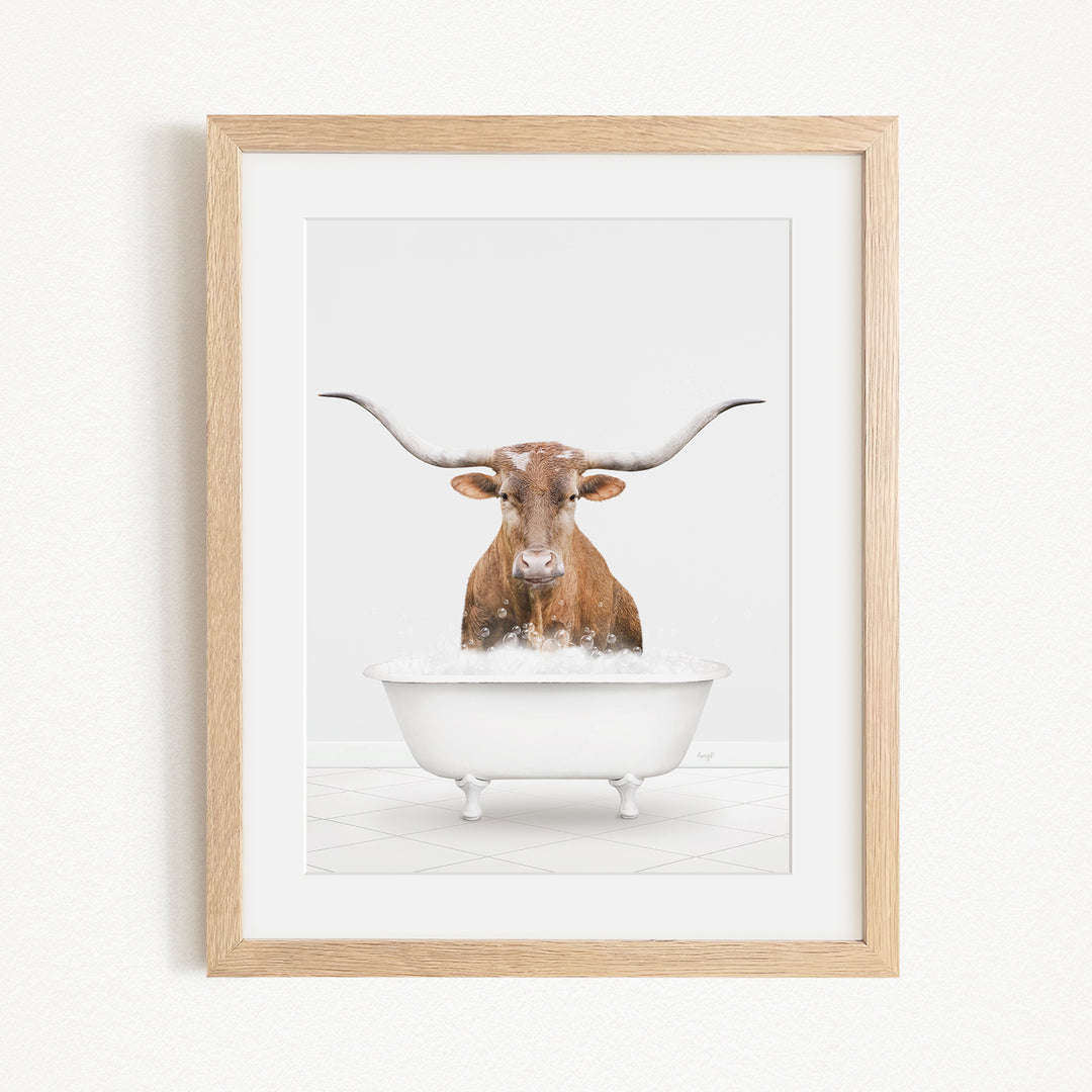 A brown cow with long horns is sitting in a white bathtub filled with water, creating a whimsical and humorous scene.