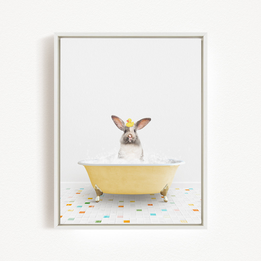 A gray rabbit sitting in a yellow bathtub filled with water, surrounded by colorful tiles on the floor.