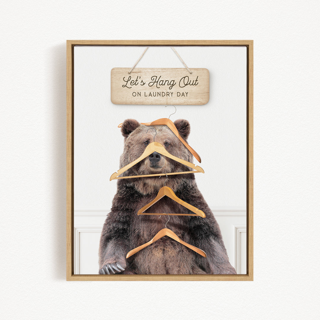 A framed image of a bear sitting on a shelf with a sign above it that says "Let's Hang Out on Laundry Day".