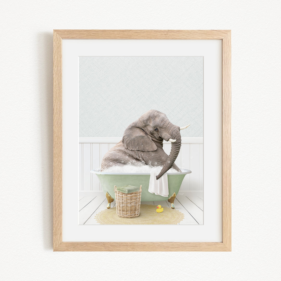 A gray elephant is sitting in a green bathtub filled with bubbles, surrounded by a basket of toys and a yellow rubber ducky.