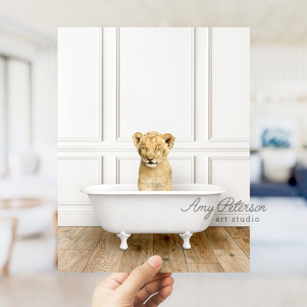 a hand holding a photo of a baby lion in a bathtub